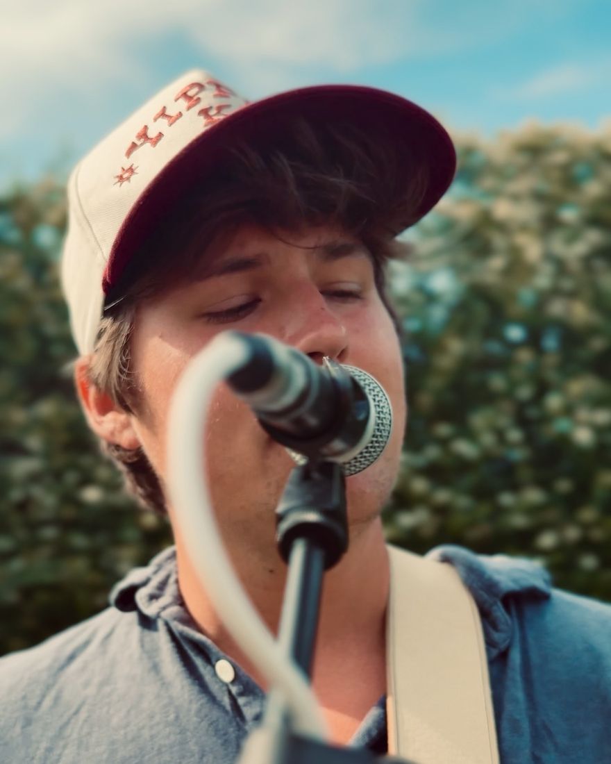 Jimmy Denny singing and playing guitar at an outdoor show